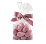 Migdał w białej czekoladzie barwiony na różowo w foliowym opakowaniu z kokardą